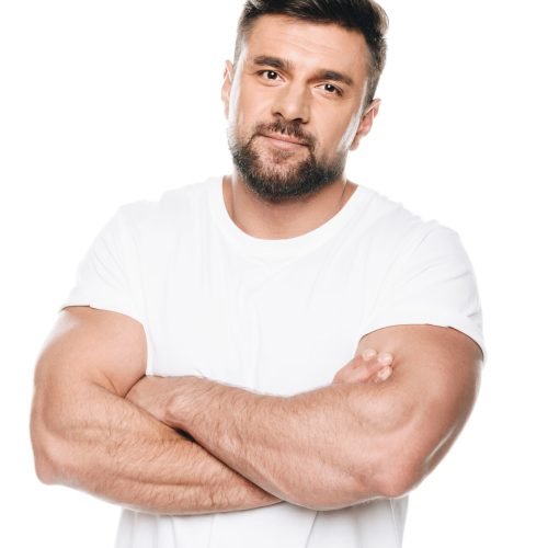 Portrait of confident bearded man posing with arms crossed and looking at camera isolated on white