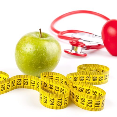 wet apple close-up with drops and yellow measure tape and red stethoscope and heart isolated on white