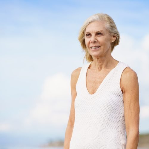 Portrait of mature woman walking on the beach. Elderly female enjoying her retirement at a seaside location.
