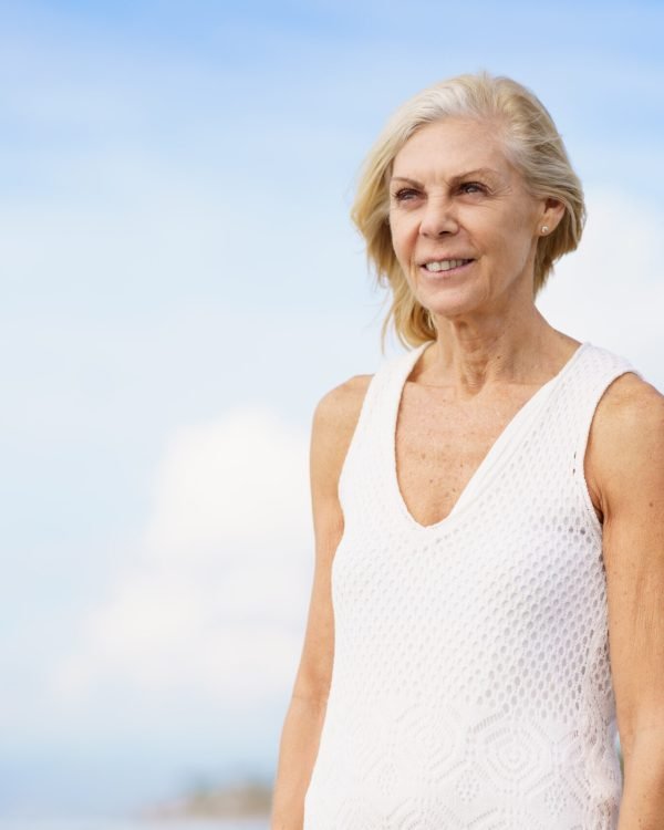 Portrait of mature woman walking on the beach. Elderly female enjoying her retirement at a seaside location.